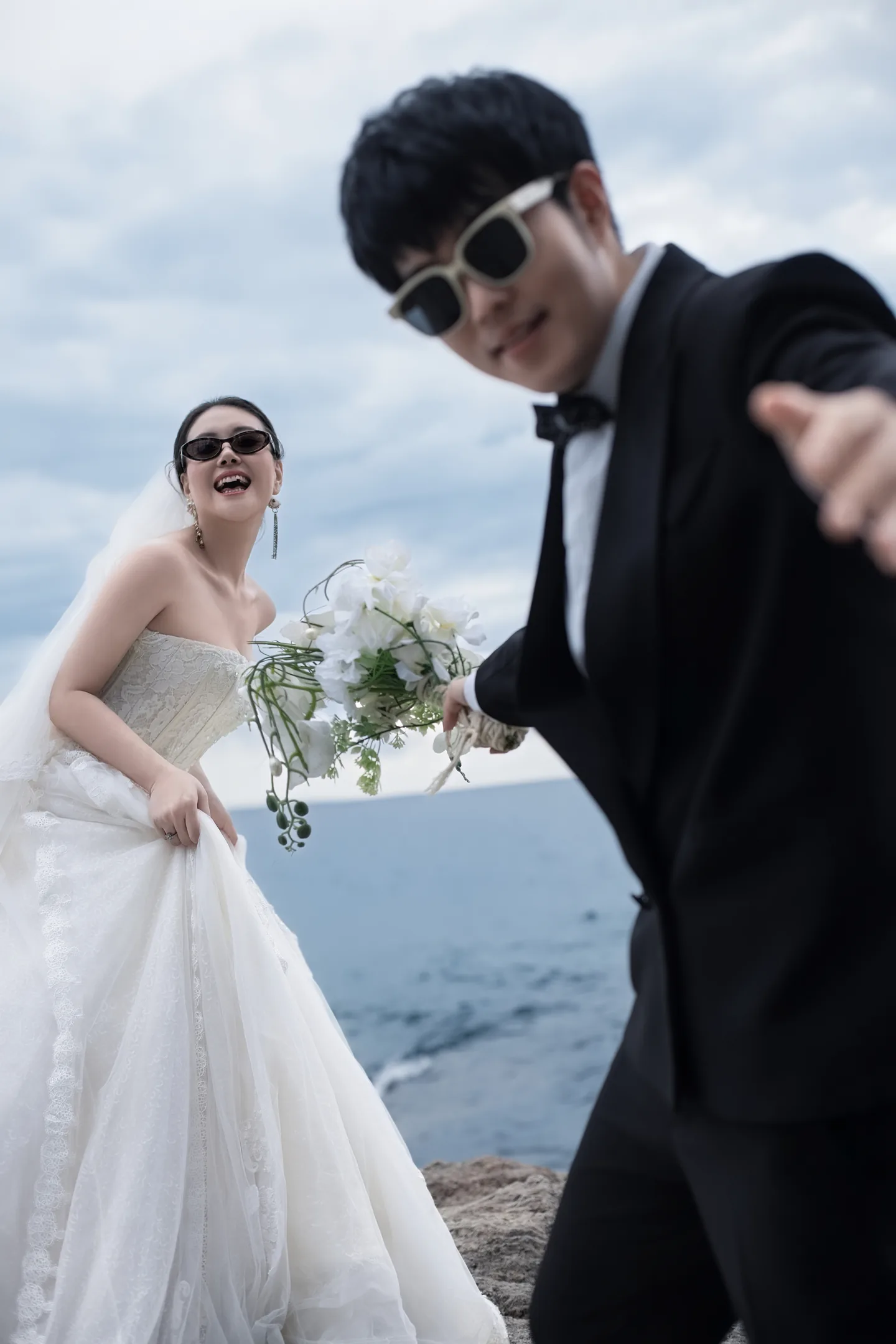 新人在海边穿着婚纱礼服的欢乐合影